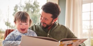 Pai lê livro com filha como síndrome de down