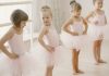 Quatro meninas fazem aula de balé com collant e saia rosa