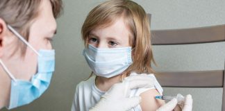 Menina de máscara recebe vacina no braço, Pfizer foi liberada para bebês de 6 meses a crianças de 4 anos