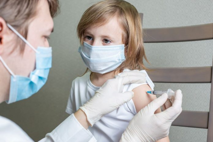 Menina de máscara recebe vacina no braço, Pfizer foi liberada para bebês de 6 meses a crianças de 4 anos