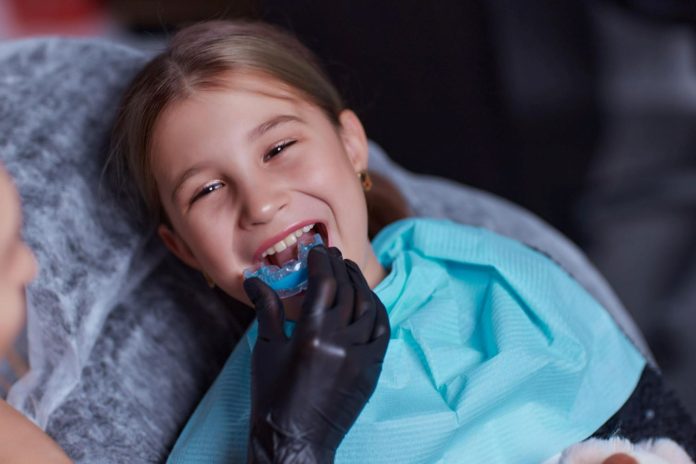 Dentista põe protetor bucal em menina