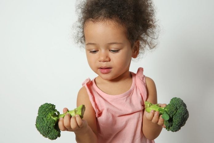Menina segura brócolos nas duas mãos