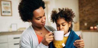 Mãe dá xícara de chá à filha doente