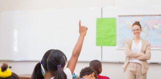 Aluna em sala de aula levanta o braço