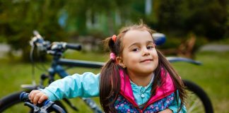 Menina sorridente segura sua bicicleta