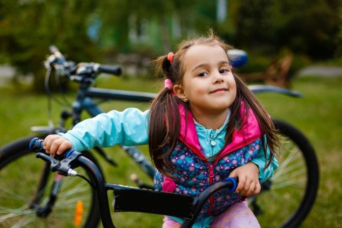 Menina sorridente segura sua bicicleta