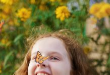 menina na natureza com borboleta pousada no nariz