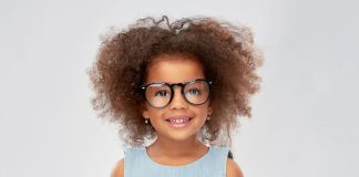 Menina negra de cabelos crespos usa óculos de grau
