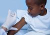 Menino negro recebe vacina no braço