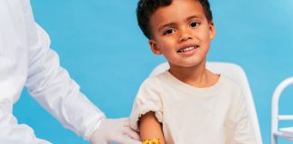 Profissional de saúde coloca bandaid no braço de menino