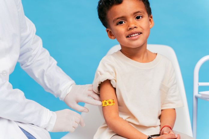 Profissional de saúde coloca bandaid no braço de menino