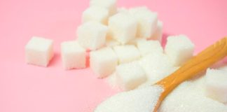 Açúcar granulado e cubos de açúcar em um fundo rosa