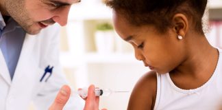 Profisisonal da saúde aplica vacina em menina negra