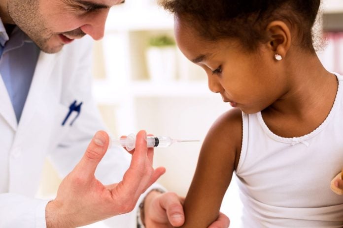 Profisisonal da saúde aplica vacina em menina negra