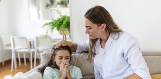 Tosse, vômitos e dor abdominal: saiba como lidar com as queixas mais comuns na pediatria; criança doente assoando o nariz e mãe a confortando