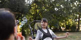 Famílias atípicas: cuidados a tomar para que as férias sejam tranquilas; menina na cadeira de rodas enquanto mãe faz bolhas de sabão