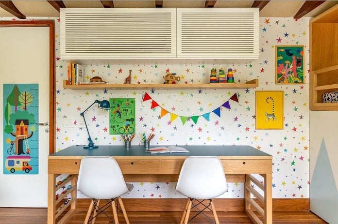 Espaço de estudos infantil com mesa eestante de madeira, bandeirolas e quadrinhos decorativos