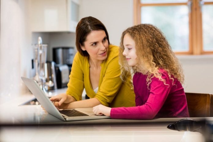 Mãe e filha navegam pela web em computador de mesa