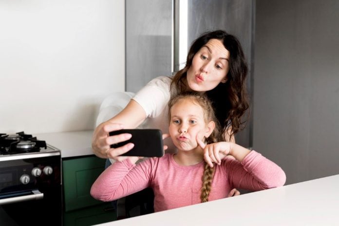 Mãe e filha fazem careta para selfie no celular