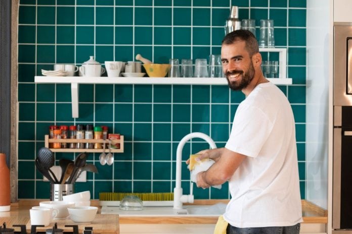 Homem sorridente lava a louça