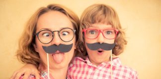 Mãe e filho seguram bigode postiço e fazem caretas engraçadas