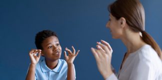 Menino gesticula com as mãos e olha para mulher adulta; diagnóstico de autismo aumenta nos EUA