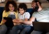 Criança olha para tela de tablet junto com pai e mãe