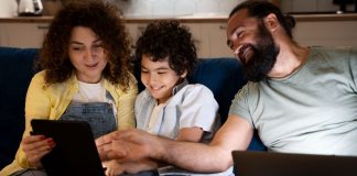 Criança olha para tela de tablet junto com pai e mãe