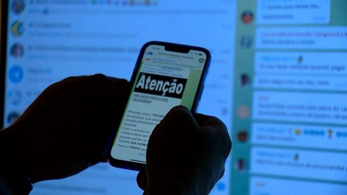 Mãos seguram um celular e na tela está escrito 