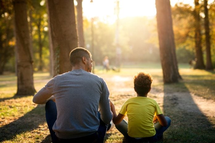 Pai e filho estão sentados ao ar livre conversando