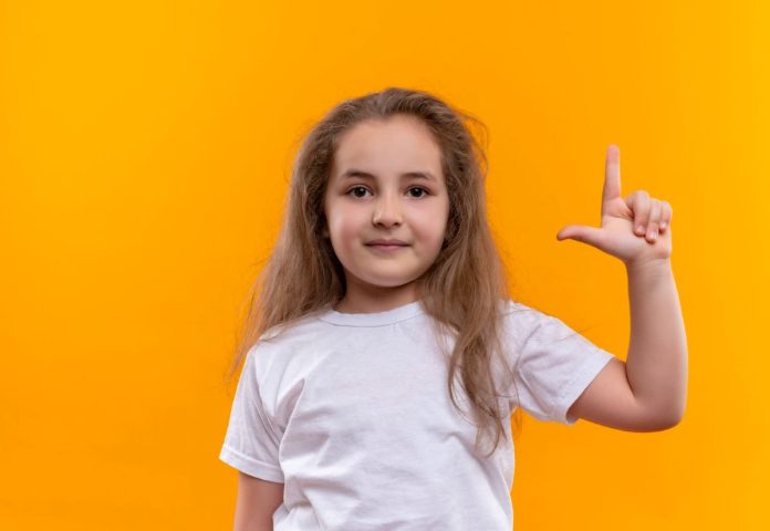 Criança faz o gesto que representa o L na língua de sinais