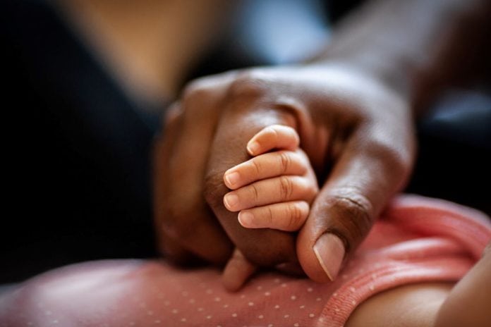 Mão de mãe negra segura mãe de bebê recém-nascido