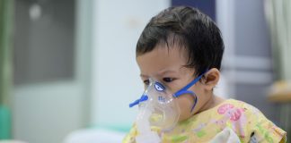 Criança pequena com Síndrome Respiratória Aguda Grave faz inalação em hospital
