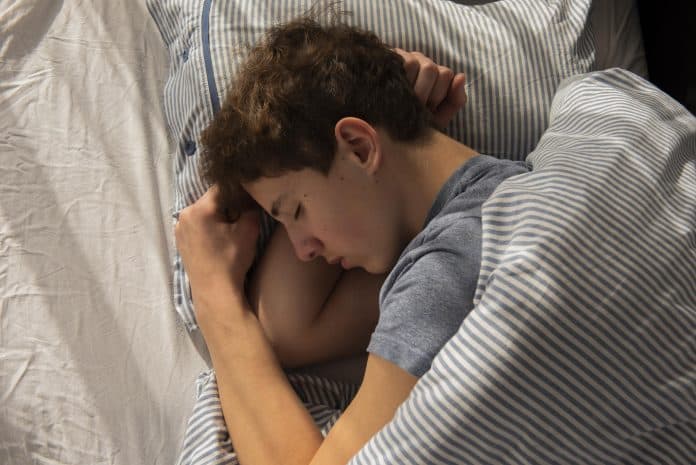 Como funciona o sono dos adolescentes?; menino adolescente dormindo