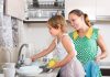Filhos que participam de tarefas domésticas são mais bem-sucedidos; menina ajudando a mãe a lavar a louça