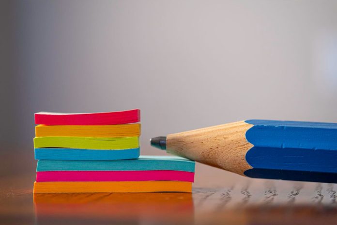 Lápis está apoiado em bloco de notas colorido