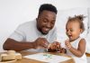 Pai brinca com filho na mesa; infância é uma fase crucial para o desenvolvimento infantil
