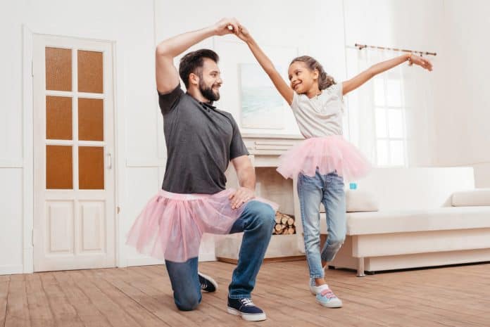 Pai praticando balé com sua filha na sala de casa