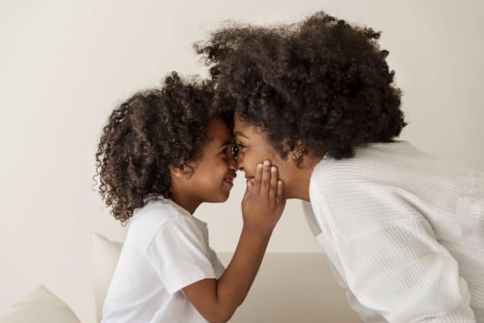 Mãe afro encosta testa com testa do filho; abordagem da parentalidade consciente propõe evitar repetir traumas da nossa criação na infância
