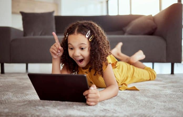 Criança sorridente olha para tela de tablet
