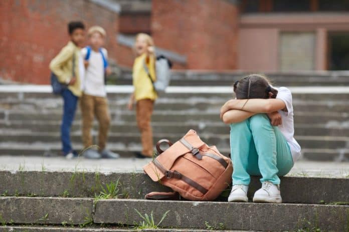 Na escola, crianças zombam de aluna que sofre bullying esconde rosto entre os braços