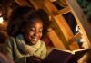 Menina negra lê livro sorridente