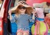 Menina de chapéu e óculos de sol no porta mala do carro
