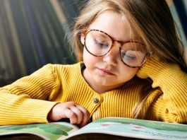 Menina de óculos lê livros durante processo de alfabetização