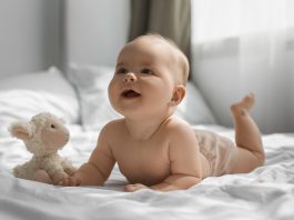 Bebê deitado de barriga para baixo com bicho de pelúcia; Miguel e Helena são os nomes mais populares de 2023 no Brasil