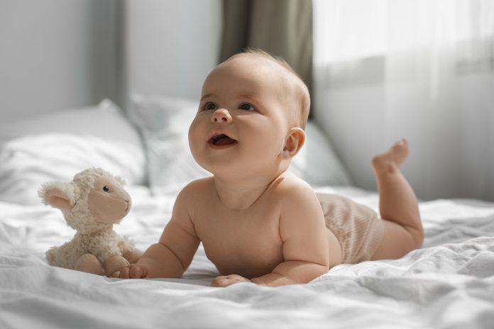 Bebê deitado de barriga para baixo com bicho de pelúcia; Miguel e Helena são os nomes mais populares de 2023 no Brasil
