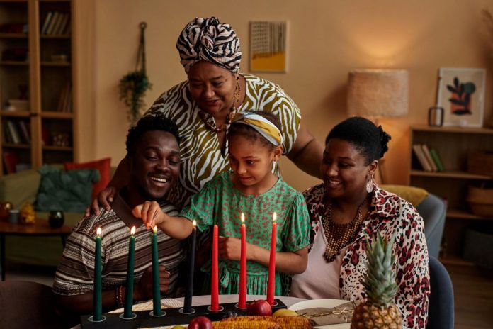 Família negra acende vela conforme tradição da celebração de Kwanzaa