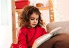 Menina de blusa vermelha lê obra; livros são uma boa opção de presente para o Natal