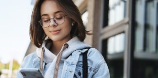 Menina olhando para celular e sorrindo; 1 em cada 5 adolescentes usa redes sociais, diz pesquisa