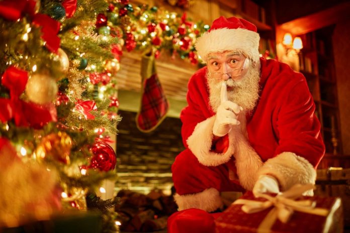 Papai Noel faz sinal de silêncio com o dedo sobre a boca